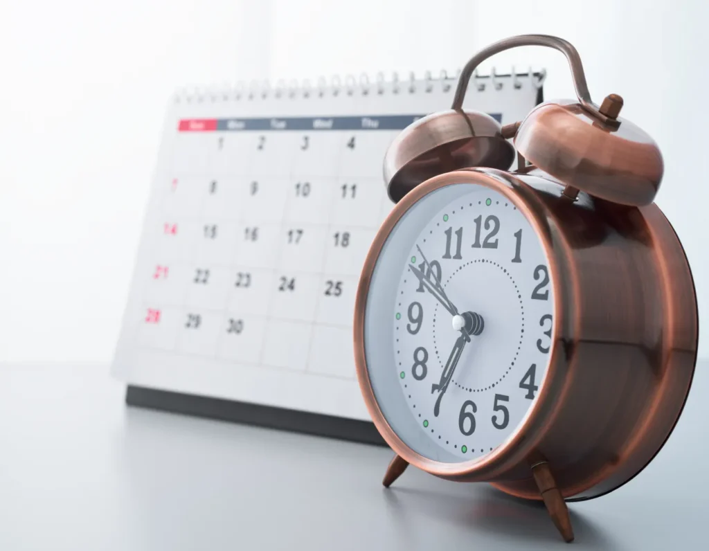 Alarm clock next to stand up calendar on a table